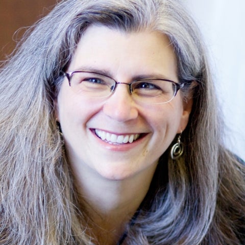 Risa Brainin smiles wearing glasses and smiling