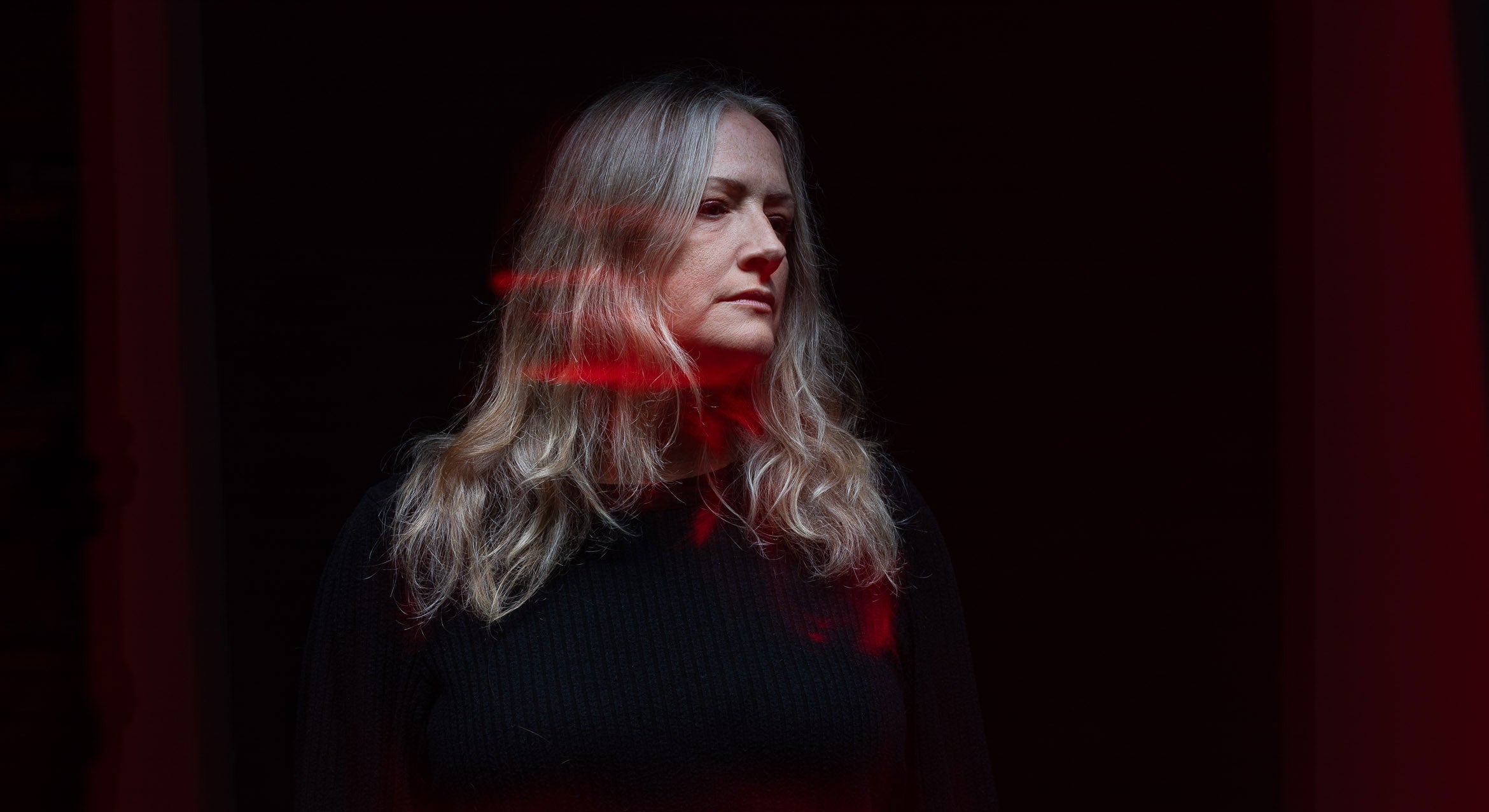 woman in dark light and shadow with red streaks of light