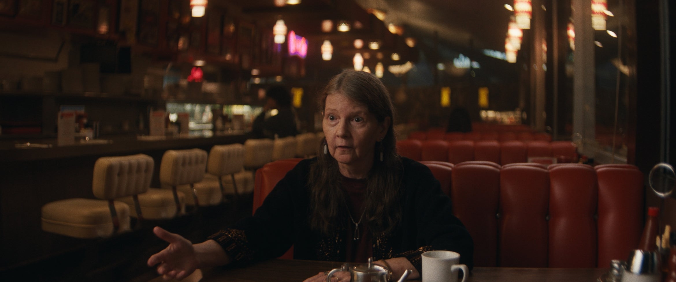A women sitting in a red vinyl booth inside a diner