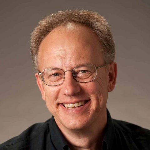 Joel Rothman smiles, wearing a black collared shirt
